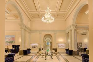 a lobby with a table and chairs and a chandelier at GH Palazzo Suite & SPA in Livorno