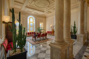 a lobby with a column and chairs and tables at GH Palazzo Suite & SPA in Livorno