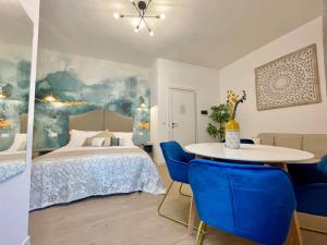 a bedroom with a bed and a table with blue chairs at BARIROOMS - Melo Suites in Bari