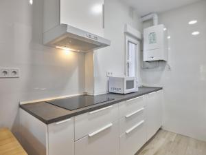 een keuken met witte kasten en een magnetron bij NEW Apto 3 DORMITORIOS 15 min a Sol en metro in Madrid