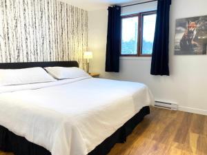 a bedroom with a large white bed and a window at Chalets Montmorency Mont-Sainte-Anne in Saint-Férréol-les-Neiges