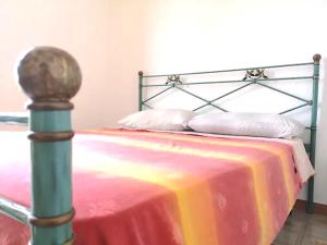 uma cama com uma armação de metal e um cobertor colorido em Eco House San Michele em San Michele