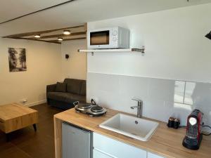 a kitchen with a sink and a microwave on a wall at Studio de charme proche Nantes & aéroport au calme in Rezé