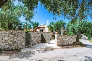 a stone fence with a gate in front of a house at Aristea Villa by PaxosRetreats in Gaios