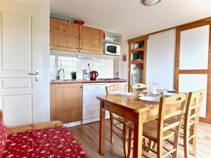 a kitchen with a wooden table and chairs in a kitchen at Appartement 3* avec terrasse plein sud, proche pistes et commerces à Chamrousse - FR-1-549-92 in Chamrousse