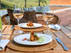 una mesa de madera con dos platos de comida y copas de vino en Zulu Waters Game Reserve, en Estcourt