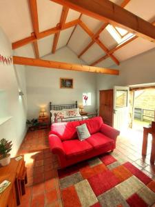 a living room with a red couch and a bed at Luddie's Country Cottages - Poppy Cottage in Aislaby