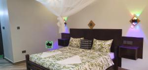 um quarto com uma cama grande e luzes roxas em Lala Inn Kikopey em Gilgil