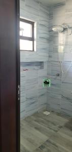 uma casa de banho com um chuveiro com azulejos azuis em Lala Inn Kikopey em Gilgil