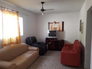 - un salon avec un canapé, une chaise et une télévision dans l'établissement Casa em Olímpia, à Olímpia