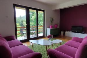 a living room with purple couches and a table at Villa Ramonda in Dolna Matka