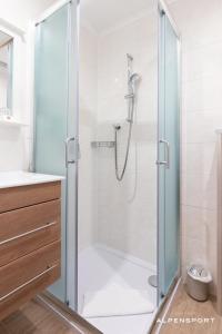 a shower stall with a glass door and a shower curtain at Gasthof Alpensport in Saalbach-Hinterglemm