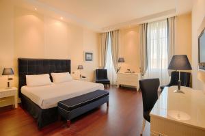 a bedroom with a bed and a desk and a chair at GH Palazzo Suite & SPA in Livorno