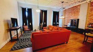 a living room with a red couch and a brick wall at Family-Friendly 3 bedroom in Historic building! in Lynchburg