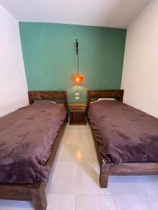 2 camas en una habitación con paredes verdes en Casa Tequio, en San Cristóbal de Las Casas