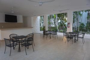 a group of tables and chairs in a room with windows at Casa Jaguar in Puerto Morelos