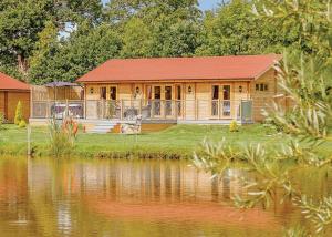 a log cabin with a lake in front of it at Gadlas Park Holiday Cabins in Ellesmere