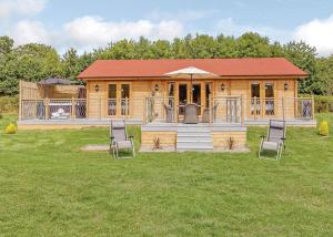 a log cabin with a deck and chairs in a field at Gadlas Park Holiday Cabins in Ellesmere