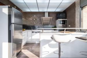 a kitchen with white cabinets and a stainless steel refrigerator at Villa Luxury Rock Tirri in Reus