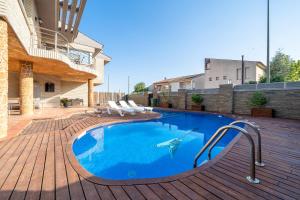 a swimming pool on a wooden deck with chairs around it at Villa Luxury Rock Tirri in Reus