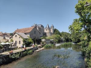 a river in a village with a castle in the background at La Maison des Roses 1-Bed House in Genouille in Génouillé