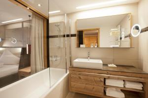 La salle de bains est pourvue d'un lavabo, d'une douche et d'un miroir. dans l'établissement Hotel Walliserstube, à Damüls