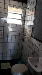ein Badezimmer mit einer weißen Toilette und einem Waschbecken in der Unterkunft Residencial Albatroz in Caraguatatuba