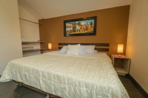 1 dormitorio con 1 cama blanca grande y 2 lámparas en B&B Wasi Airport Lima, en Lima