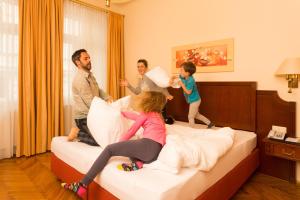 ウィーンにあるシティ アパートメンツ ホテル シティ セントラルのホテル内のベッドで遊ぶ家族