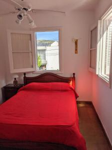 Cama roja en habitación con ventana en Blau Hostel en Villa Carlos Paz