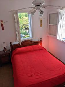 1 cama roja en un dormitorio con ventana en Blau Hostel en Villa Carlos Paz