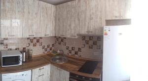 a kitchen with a counter with a sink and a microwave at Ауэзова 49б, 2х комнатная in Ustʼ-Kamenogorsk