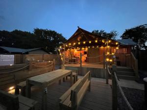 una terraza con mesa y una tienda con luces en Jungle Book Safari Tent en Tenby