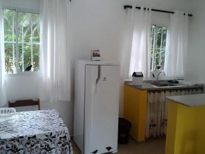 a kitchen with a white refrigerator and a table at Maresias Flats Unidade I in Maresias
