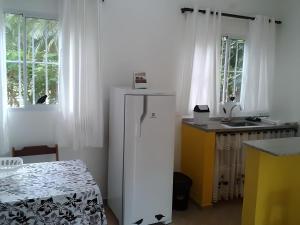 a kitchen with a white refrigerator and a table at Maresias Flats Unidade I in Maresias