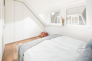 a white bedroom with a bed and a window at Stewohood Norderney in Norderney