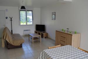 um quarto com uma cama, uma televisão e uma cadeira em Maison de 3 chambres avec vue sur la mer jardin clos et wifi a Saint Laurent sur Mer em Saint-Laurent-sur-Mer