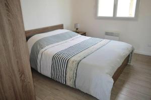 um quarto com uma cama com um cobertor listrado em Maison de 3 chambres avec vue sur la mer jardin clos et wifi a Saint Laurent sur Mer em Saint-Laurent-sur-Mer