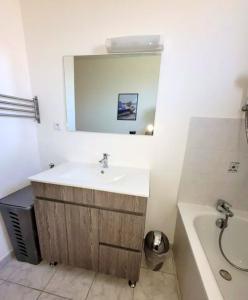 uma casa de banho com um lavatório, uma banheira e um espelho. em Maison de 3 chambres avec vue sur la mer jardin clos et wifi a Saint Laurent sur Mer em Saint-Laurent-sur-Mer