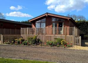 a house with a fence and flowers in front of it at Kings Lynn Holiday Park in King's Lynn