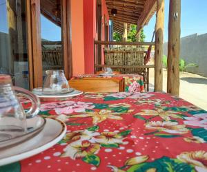 a table with a red table cloth with flowers on it at Natal Chalés Nova Caraiva in Caraíva
