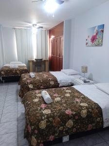 Cette chambre d'hôtel comprend 3 lits avec des fleurs. dans l'établissement Hospedaje Petro Talara, à Talara