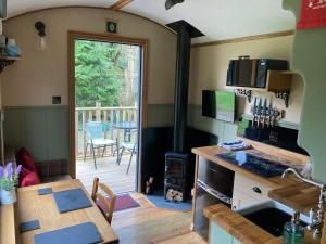 a kitchen and dining room with a wood stove at Brook the Shepherd Hut in Saltash
