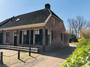 une ancienne maison en briques avec un toit noir dans l'établissement Brinkzate - De Brink, à Dwingeloo
