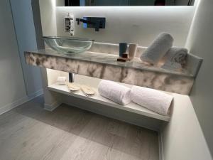 a bathroom with a counter with towels and a sink at Porto Covo Praia Hotel & SPA in Porto Covo