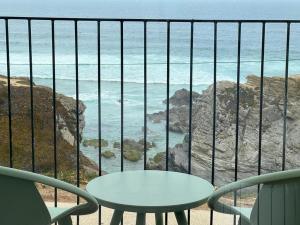 a balcony with a table and chairs and the ocean at Porto Covo Praia Hotel & SPA in Porto Covo