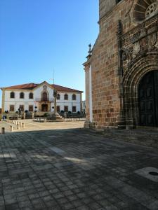 a large brick building with a stone courtyard in front at Casa da Muralha in Vila Nova de Foz Coa