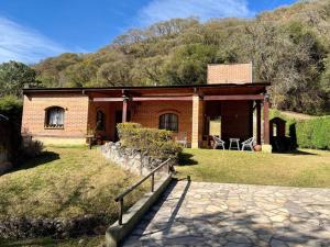 a small brick house with a hill in the background at Pintoresca casa con pileta in Yala