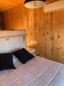 1 dormitorio con 1 cama grande y paredes de madera en Cabaña para dos personas en Punta de Lobos PUERTO LA MAR, en Pichilemu