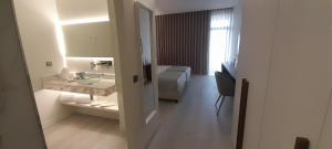 a bathroom with a sink and a bed in a room at Porto Covo Praia Hotel & SPA in Porto Covo
